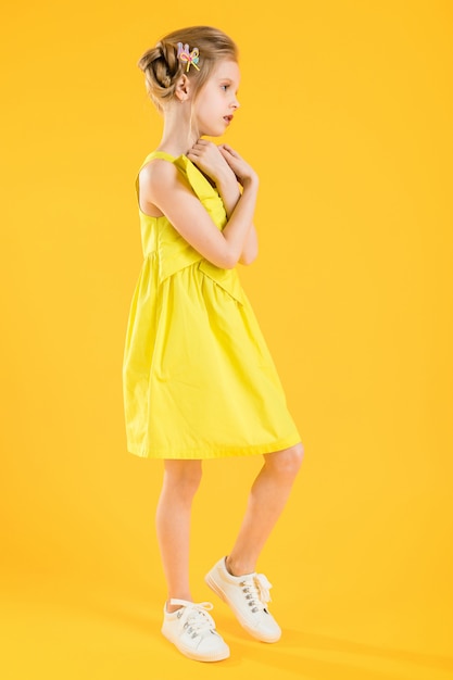 Mädchen posiert auf gelbem Kleid.