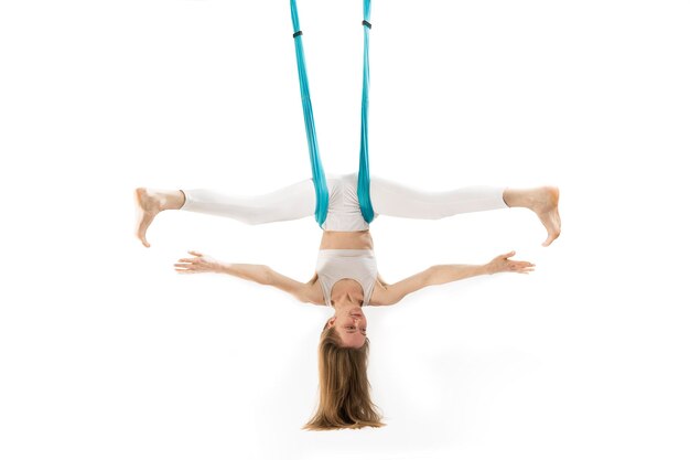 Mädchen praktiziert Fly Yoga kopfüber hängend auf Sporthängematte isoliert auf weißem Hintergrund Luftgymnastik