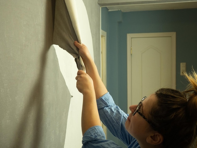 Foto mädchen reißt alte tapeten ab und renoviert die wohnung