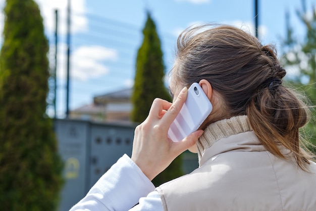 Mädchen ruft über Smartphone an, während sie die Straße entlang geht.