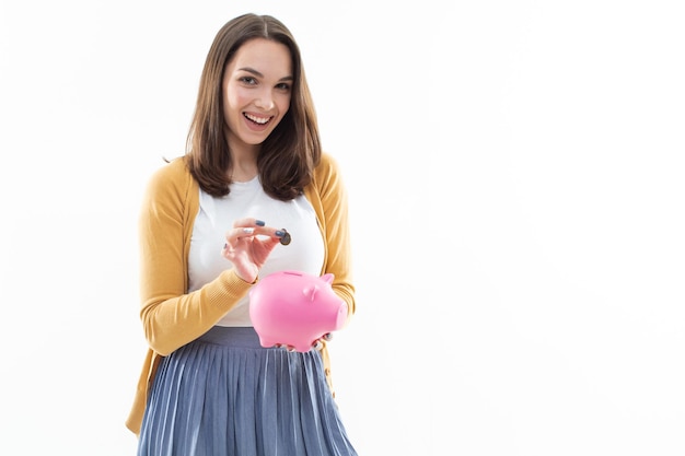 Mädchen sammelt Geld in einem rosa Sparschwein auf weißem Hintergrund