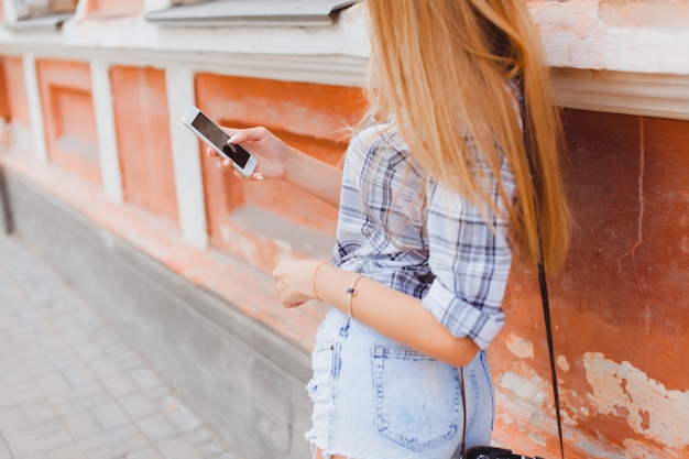 Mädchen schaut auf ihr Handy auf der Straße