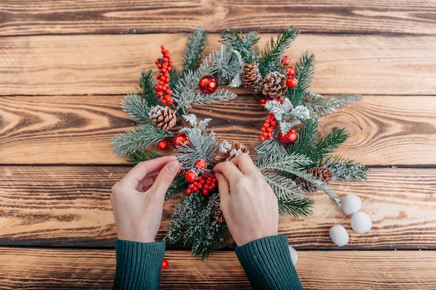 Mädchen schmückt einen Weihnachtskranz auf einem Holztisch.