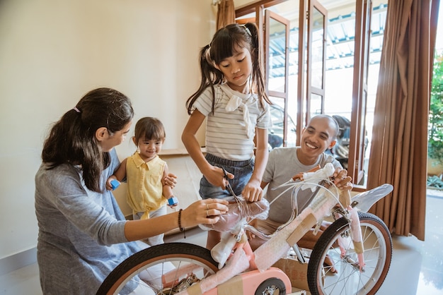 Mädchen schneidet Plastikfolie, während sie ein neues Mini-Bike hält