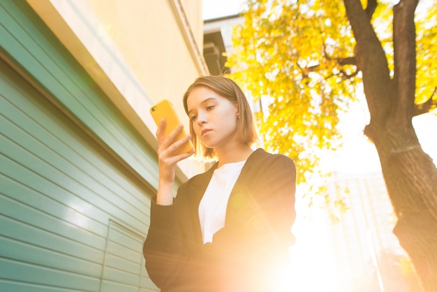 Mädchen schreibt eine Nachricht auf einem Smartphone mit einem Gegen-Sonnenlicht