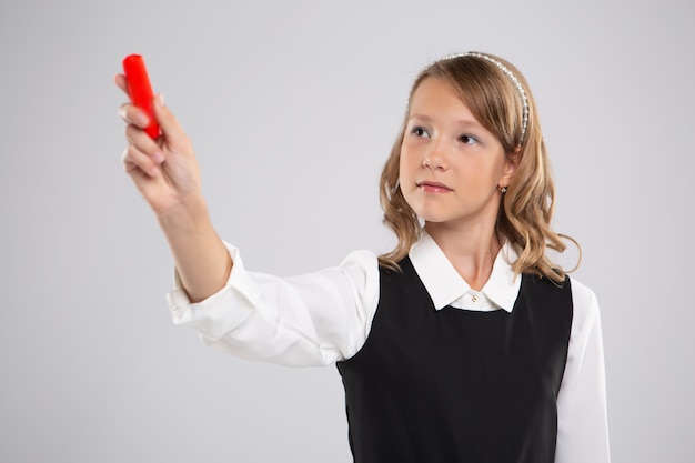 Mädchen Schulmädchen schreibt an die Tafel mit roter Kreide.