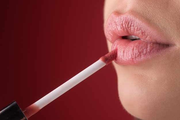 Mädchen setzt Lippenstift auf die Lippen mit einem Pinsel Nahaufnahme von Frauen Lippen mit Lippenstift Lippenstift auf eine