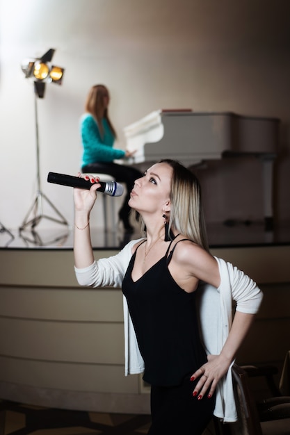 Mädchen singt in einem Restaurant, und hinter ihrem Kollegen spielt Klavier.