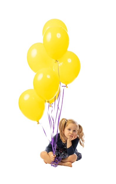 Mädchen sitzen und mit bunten Luftballons.