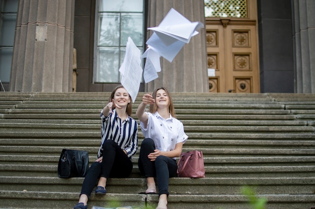 Mädchen sitzen und werfen Blätter Papier