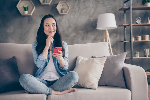 Mädchen sitzt auf dem Sofa und hält das Telefon