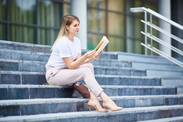 Mädchen sitzt auf den Stufen und liest ein Buch