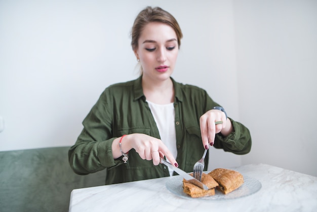 Mädchen sitzt im leichten Restaurant und isst Sandwich mit Messer und Gabel. Frau frühstückt im Cafe.