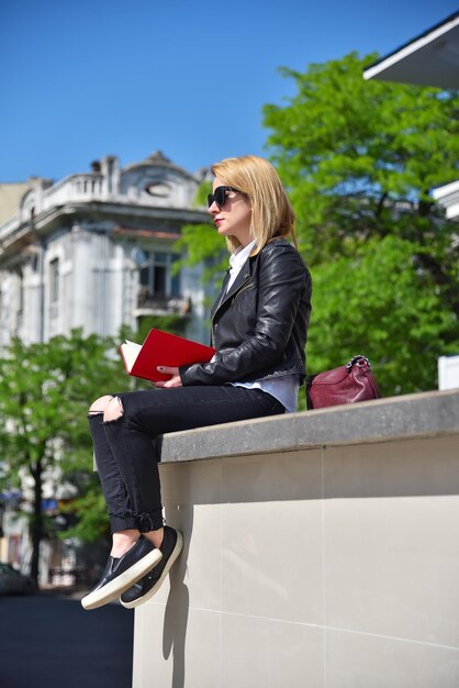 Mädchen sitzt mit Buch auf dem Dach