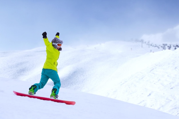 Mädchen-Snowboarder, der in den Alpen den Hang hinunterläuft. Wintersport und Erholung, Freizeitaktivitäten im Freien. Bild des aufgeregten schreienden Genusskonzepts der jungen Frau