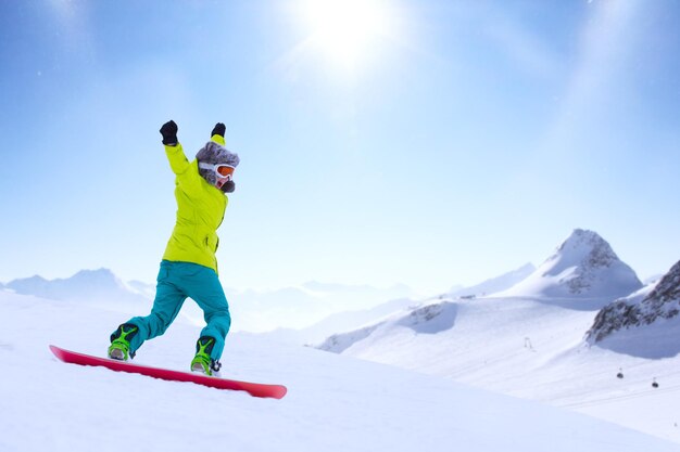 Mädchen-Snowboarder, der in den Alpen den Hang hinunterläuft. Wintersport und Erholung, Freizeitaktivitäten im Freien. Bild des aufgeregten schreienden Genusskonzepts der jungen Frau