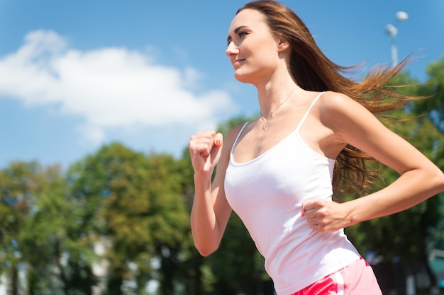 Mädchen sonnig im Freien am blauen Himmel. Coach oder Trainer beim Training. Sport und gesunde Fitness. Runner auf Wettbewerb und zukünftigen Erfolg. Frau läuft auf Arenabahn.