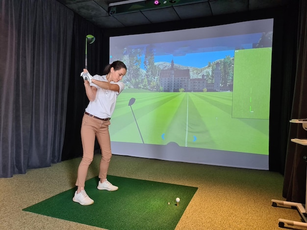 Mädchen spielen Golf auf dem Bildschirm und Golfsimulator