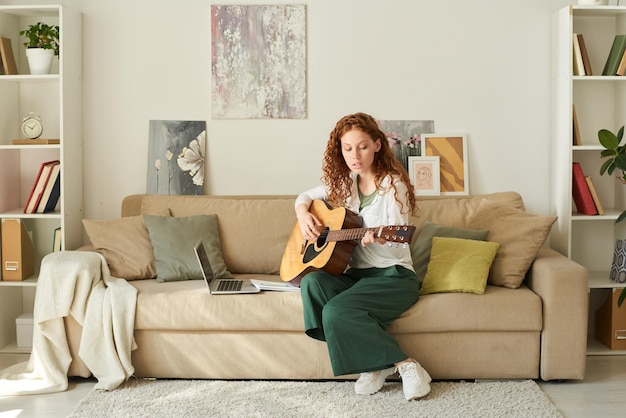 Mädchen spielt Gitarre im Wohnzimmer