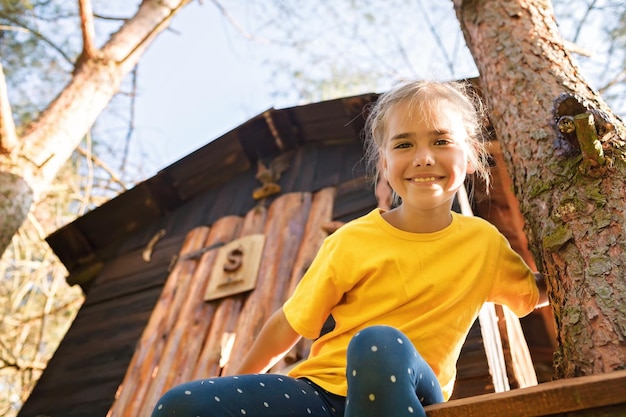 Mädchen spielt in kreativem, handgefertigtem Baumhaus im Hinterhof Sommeraktivität glückliche Kindheit Cottagecore