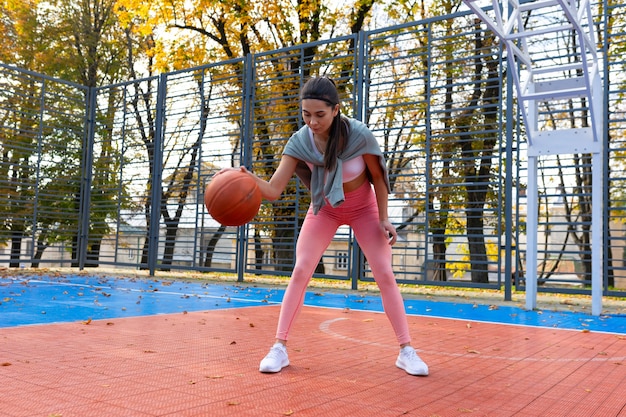 Mädchen spielt mit Ball auf einem Basketballplatz