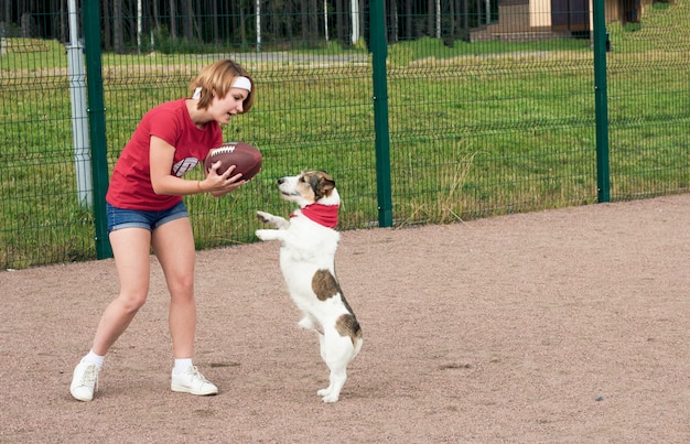 Mädchen spielt mit ihrem Hund im American Football.