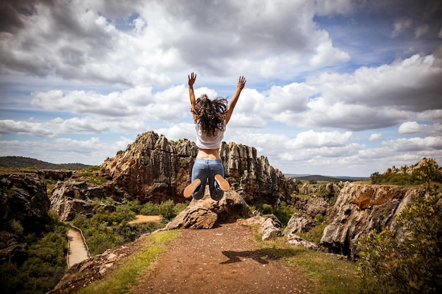 Mädchen springen vor Freude in einer spektakulären natürlichen Berglandschaft mit Felsen
