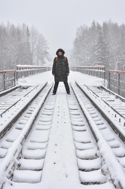 Mädchen steht auf der Eisenbahn im Schnee