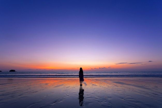 Mädchen steht beim Sonnenuntergang am Strand