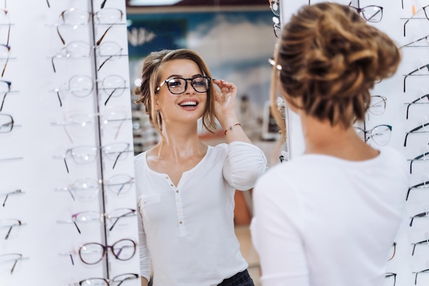 Mädchen steht mit Brille im Hintergrund im Optikgeschäft. Stehen Sie mit Brille. Korrektur des Sehvermögens. Frau trägt eine Brille.