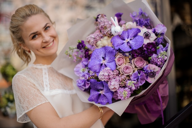 Mädchen steht mit einem vollständig purpurroten Blumenstrauß