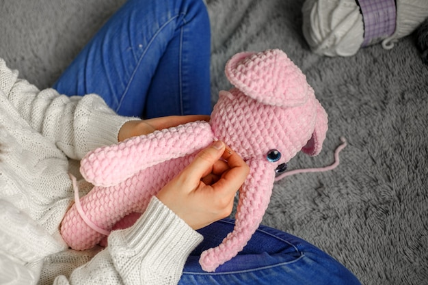 Mädchen strickt ein Spielzeug aus rosa Garn