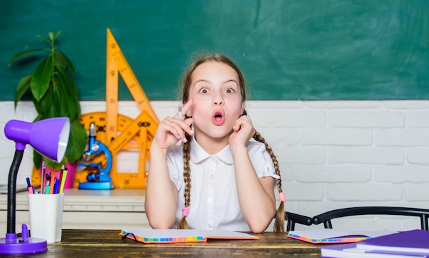 Mädchen süßes Kind sitzt in der Schule Klassenzimmer Tafel Hintergrund Kleines Kind studiert Schule Wissenstag Beschleunigung in die Zukunft Hometask-Konzept Zurück in die Schule am 1. September Verknüpft am Lernen