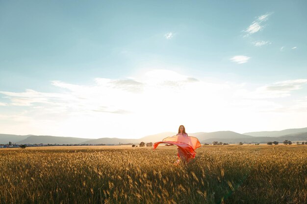 Mädchen tanzen auf einem Feld in einem schönen rosa Kleid bei Sonnenuntergang