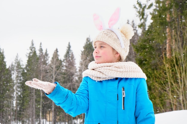 Mädchen Teenager auf der Straße ein Mädchen mit Karneval Hasenohren auf dem Kopf fängt Schneeflocken mit ihrer Handfläche