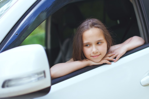 Mädchen Teenager mit langen Haaren schaut aus dem Fenster des Autos.