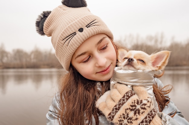 Mädchen Teenager und Chihuahua. Mädchen in einer Winterjacke über einem Fluss mit einem Hund.