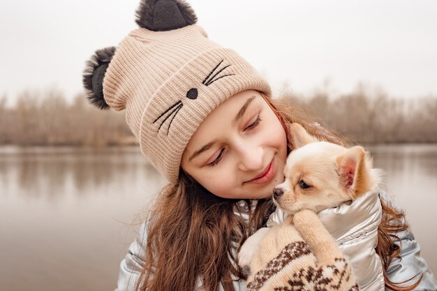 Mädchen Teenager und Chihuahua. Mädchen in einer Winterjacke über einem Fluss mit einem Hund.