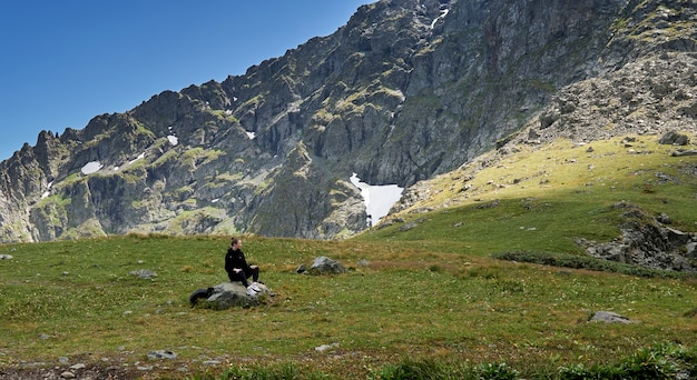 Mädchen Tourist mit einem Rucksack sitzt auf den Felsen in den Bergen. Altai