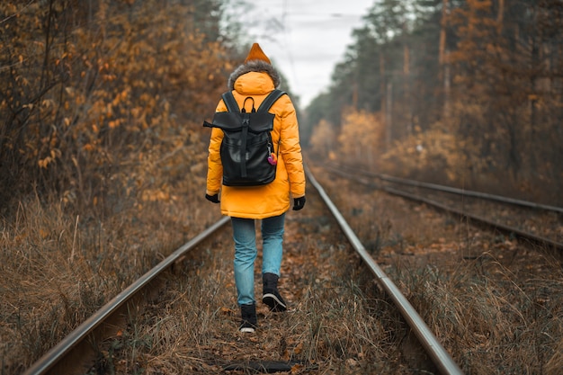 Mädchen Tourist reist durch den Herbstwald entlang der Eisenbahn.