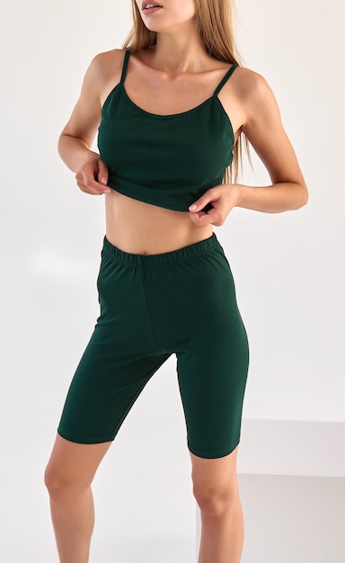 Mädchen trägt dunkelgrüne Leggings und dunkelgrünes, ärmelloses, isoliertes Sportoutfit für den Sommer