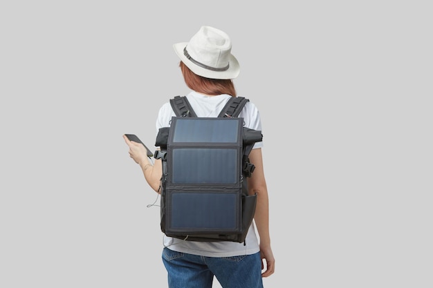 Foto mädchen trägt rucksack mit flexiblem solarpanel, das am smartphone befestigt ist, isoliert in den händen