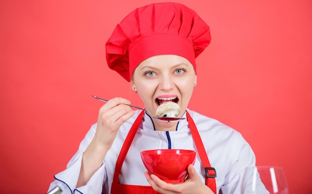 Mädchen tragen Hut und Schürze, probieren Sie den Geschmack der Mahlzeit. Gesunde Ration. Professioneller Koch der Frau hält Schüssel und Löffel. Kostenlose gesunde vegetarische und vegane Rezepte. Gesunde Rohkost. Diätkonzept. Gesund ernähren.