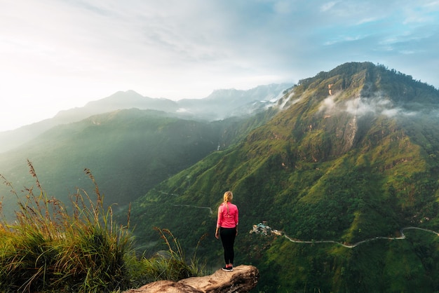 Mädchen trifft Sonnenaufgang in den Bergen. Mädchen, das nach Sri Lanka reist. Bergsport. Sportler glücklicher Abschluss. Bergtourismus. Wanderung. Die Reise in die Berge. Mann am Rande des Berges