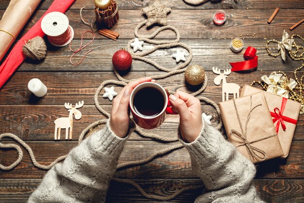 Mädchen trinken heißen tee am holztisch mit weihnachtszubehör