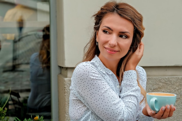 Mädchen trinkt Kaffee auf der Straße Street Cafe schönes Mädchen und Kaffee