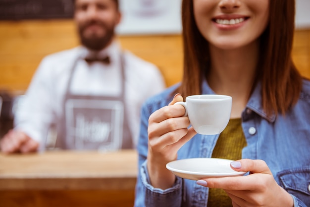 Mädchen trinkt Kaffee in einer Kaffeestube und lächelt.