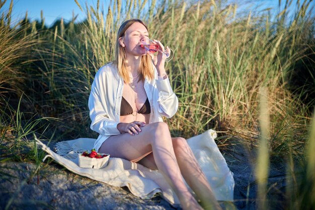 Mädchen trinkt Wein am Strand