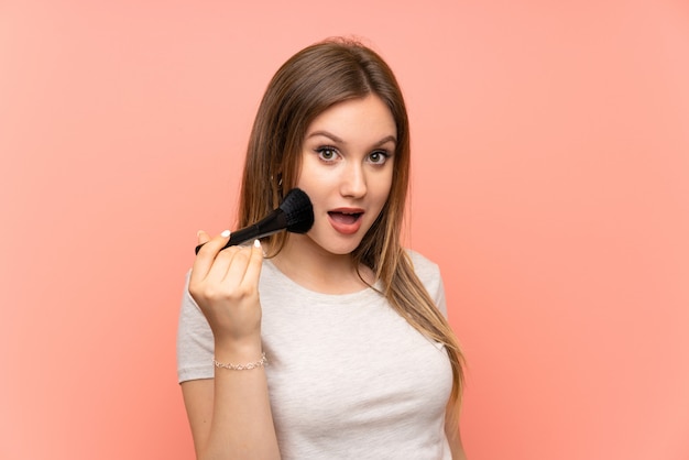 Mädchen über rosa Wand mit Make-up Pinsel