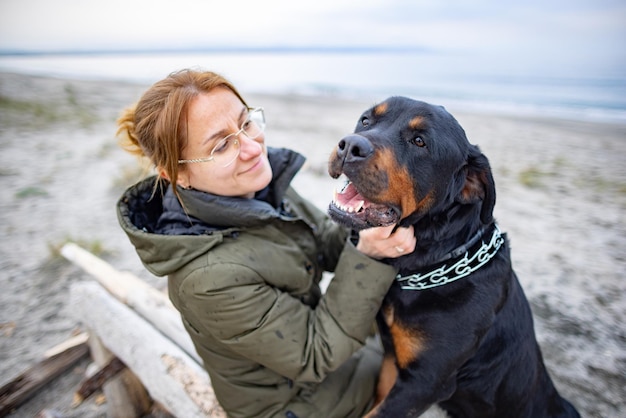 Mädchen umarmt einen Rottweiler-Hund am Strand